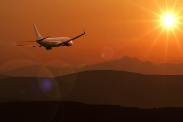 Fototapeta na wymiar Passenger plane flying over the hills towards the sun
