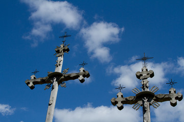 two wooden, old and ornamental crosses on a background of blue sky