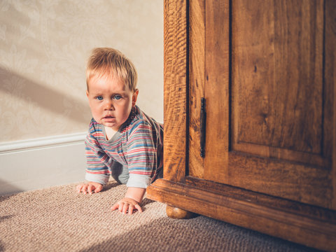 Little baby hiding behind wardrobe
