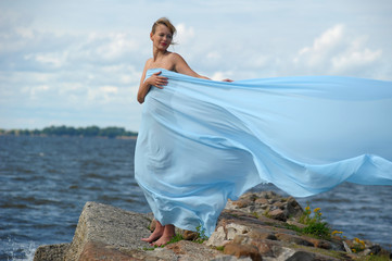 young woman standing on a promontory and enjoying the wind