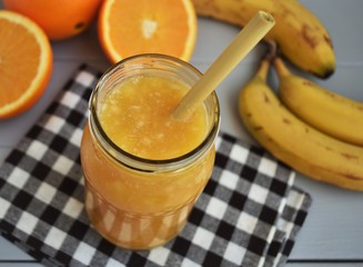 Banana and orange smoothie in jar.