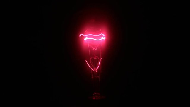 Close-up of the increase and decrease in the glow of an red incandescent lamp.