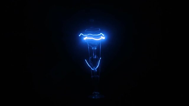 Close-up of the increase and decrease in the glow of an blue incandescent lamp.