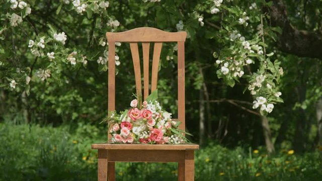 Old wooden chair with flover bouquet under the apple tree