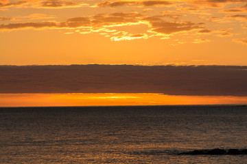 Reddish dawn in the sea and with clouds. Atmospheric phenomena concept