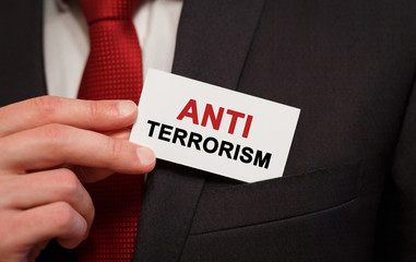 Businessman putting a card with text Anti Terrorism in the pocket