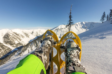Hiker looking over his snowshoes at the beautiful landscape in the French mountains during sunset