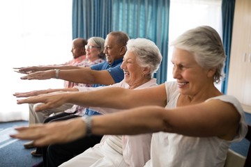 Cheerful senior people exercising with arms raised