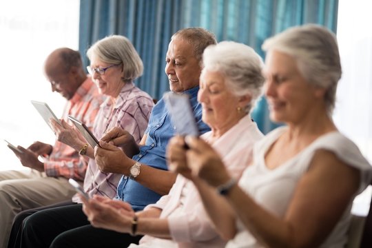Smiling senior people using digital tablets while sitting on