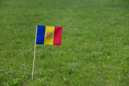 Andorra flag on a green grass lawn field background. National flag of  Andorra waving outdoors