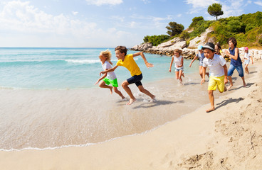 Group of happy kids racing on sandy beach