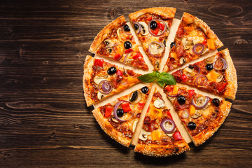 Pizza margherita with black olives on wooden background
