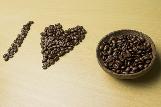 coffee concept - roasted coffee beans and coffee cup in the middle with shape i love. 