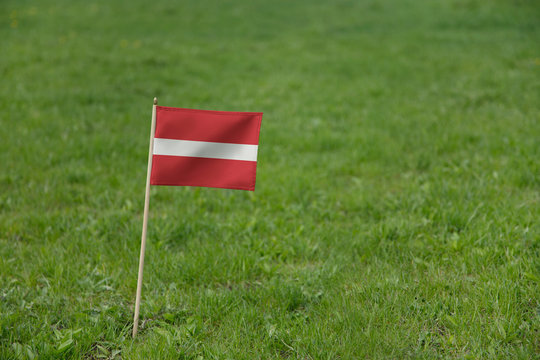 Latvia flag, Latvian flag on a green grass lawn field background. National flag of Latvia waving outdoor