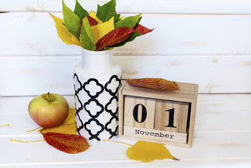 wooden calendar with 01 november  word sign and colorful autumn leaves