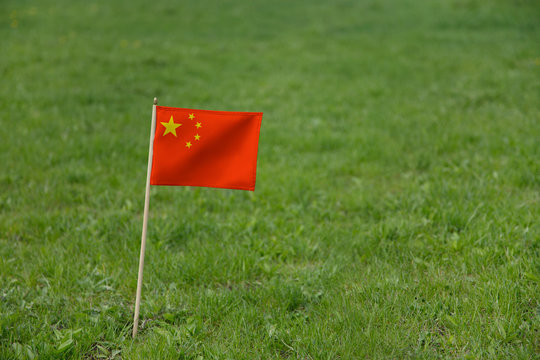 China flag, Chinese flag on a green grass lawn field background. National flag of the People's Republic of China waving outdoor