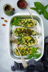 Grilled spicy zucchini with pepper and pesto sauce in aluminum form on a gray concrete background. Selective background. Top view. Copy space.