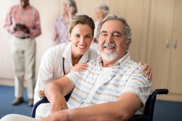 Portrait of smiling female doctor with disabled senior man