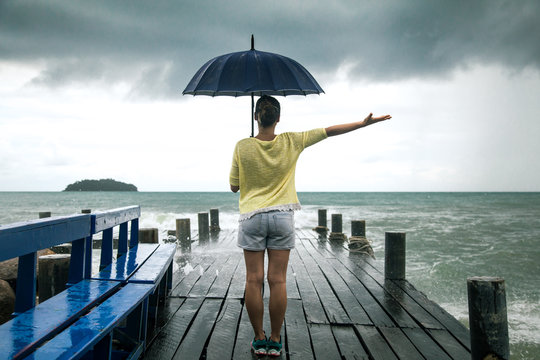 a young girl on a pier with an umbrella