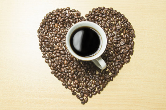 coffee concept - roasted coffee beans and coffee cup in the middle with shape love. 