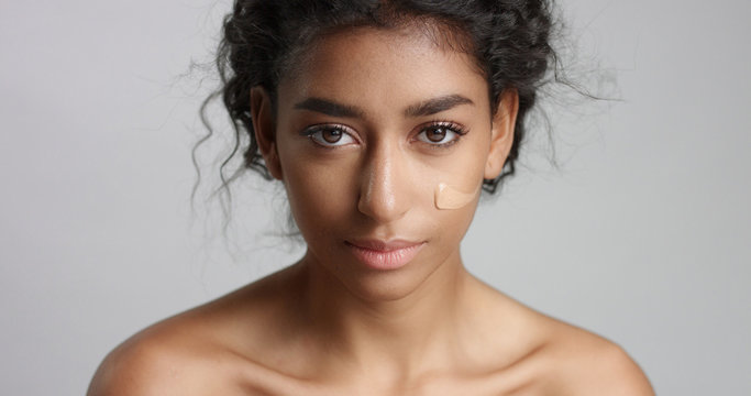 middle eastern young woman in studio with a foundation on cheek closeup