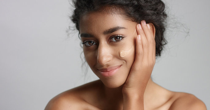 middle eastern young woman in studio with a foundation on cheek closeup