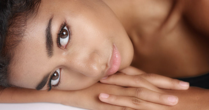 Close up shot of a pretty young wooman with smooth glowing skin relaxing on a white massage table. Studio shoot