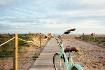 Fototapeta na wymiar Lonely beautiful mint bike on wooden boardwalk to sea with soft sunset
