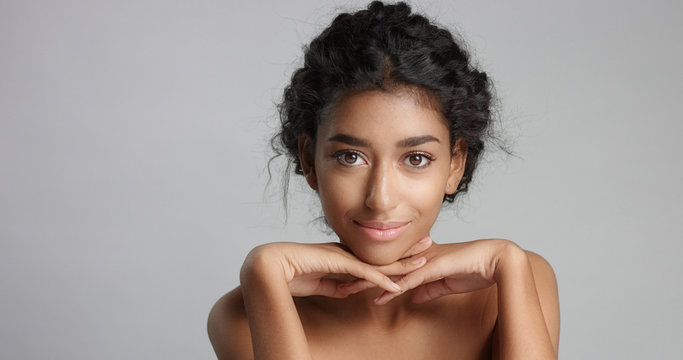 happy serene young woman with beautiful olive skin and curly hair ideal skin and brown eyes