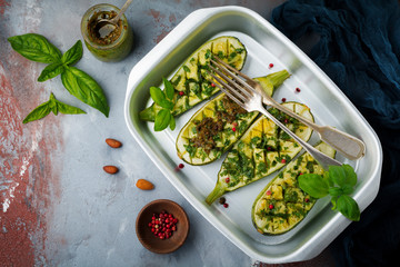 Grilled spicy zucchini with pepper and pesto sauce in aluminum form on a gray concrete background. Selective background. Top view. Copy space.