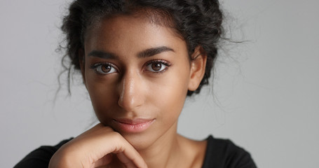 Fototapeta premium young girl with perfect light brown skin and beautiful curly black hair smiling at the camera in studio