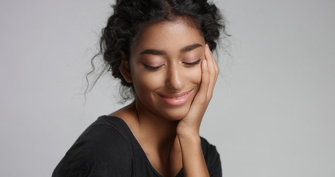 young girl with perfect light brown skin and beautiful curly black hair smiling at the camera in studio