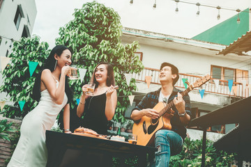 Group of young asian people happy while enjoying home party and play guitar on garden party
