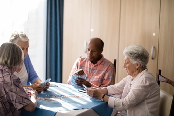Senior people playing cards at table