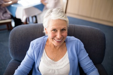 Fototapeta na wymiar High angle view of smiling senior woman sitting on armchair