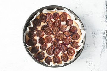 Whole plum cake on white shabby background. Top view.