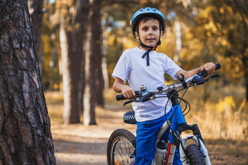 kid on a bicycle in the sunny forest. boy cycling outdoors in helmet