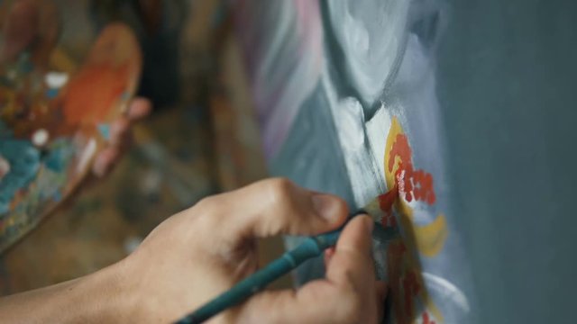 Caucasian artist painting with a brush a colourful still life picture, close-up slow motion
