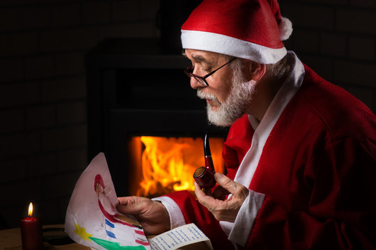 Weihnachtsmann schaut selbstgemaltes Kinderbild an