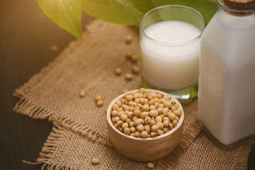 Bottle of soy milk and soybean on wooden table