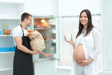 Obraz premium Pregnant woman with husband cooking food in kitchen