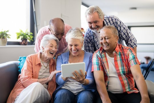 Cheerful senior friends looking at digital tablet