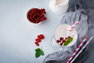 Red currant yoghurt smoothies, milkshake in a glass cup on a gray concrete background. Selective focus. Top view.