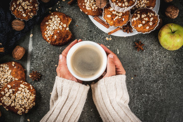 Autumn winter pastries. Vegan food. Healthy cookies, muffins with nuts, apples, oat flakes. Cozy atmosphere, warm blanket, girl drink coffee, hands in picture. Dark stone table. Copy space top view