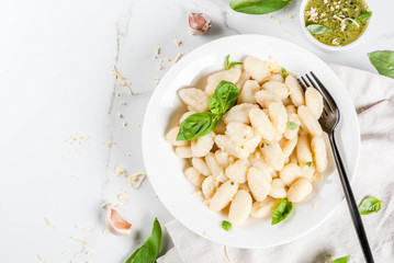 Italian food recipe, Healthy vegan dinner with potato gnocchi. With grated parmesan cheese, basil and pesto sauce. On white marble , copy space  top view