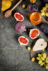 Obraz na płótnie Canvas Snacks, dietary vegan desserts. Autumn fruits (figs, pears, grapes) with honey on a black stone table. Copy space top view