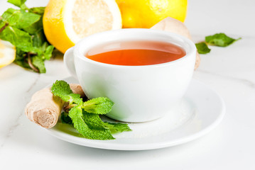Cup of ginger tea with lemon,fresh mint and honey, on white marble table, copy space