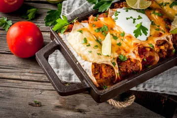 Photo sur Plexiglas Plats de repas Mexican food. Cuisine of South America. Traditional dish of spicy beef enchiladas with corn, beans, tomato. On a baking tray, on old rustic wooden background. Copy space