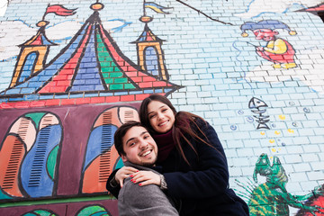 couple in love on the background of a painted wall in winter in a coat