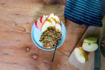 Bowl of  granola with yogurt and slide apple on wooden background from top view
